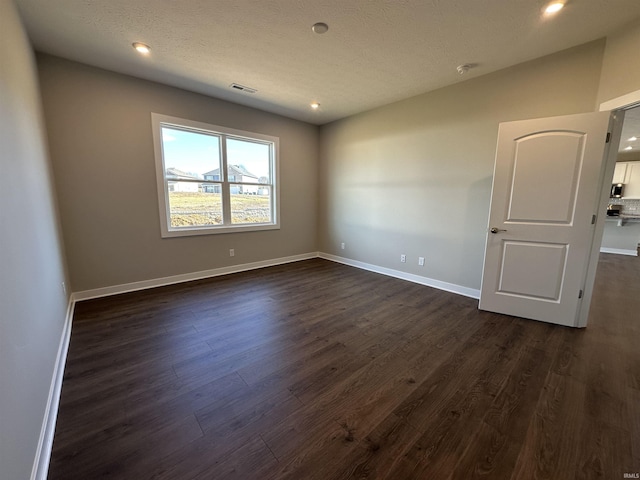 unfurnished room featuring dark wood-type flooring and a textured ceiling