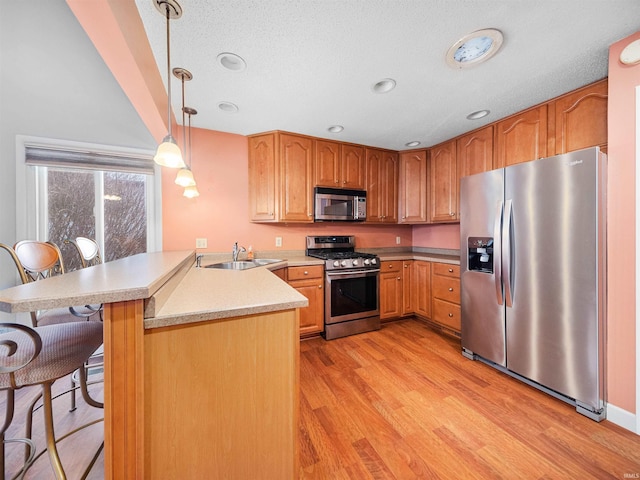 kitchen featuring pendant lighting, sink, a kitchen breakfast bar, stainless steel appliances, and kitchen peninsula