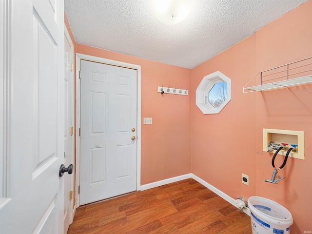 washroom with hookup for a washing machine, hookup for an electric dryer, a textured ceiling, and hardwood / wood-style flooring