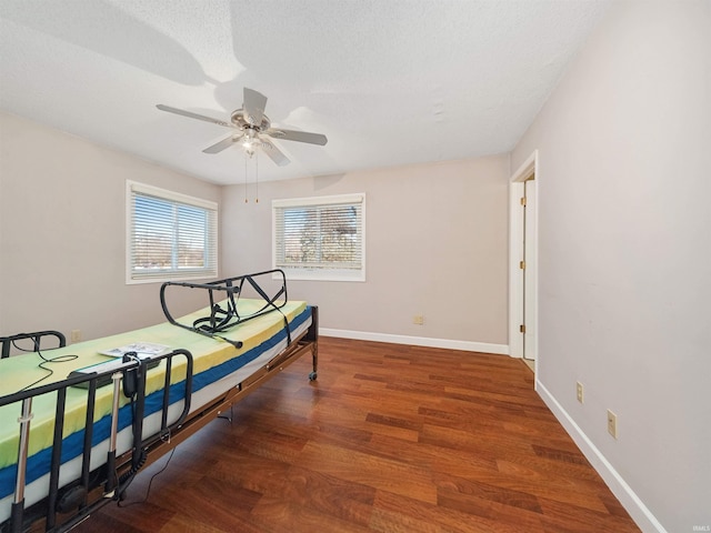 bedroom with ceiling fan, dark hardwood / wood-style floors, and a textured ceiling