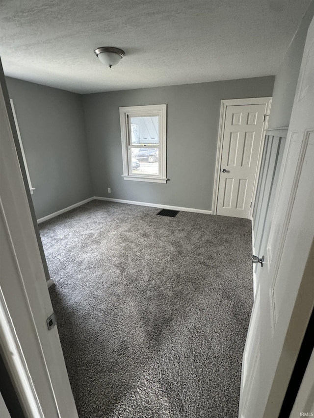 carpeted empty room featuring a textured ceiling