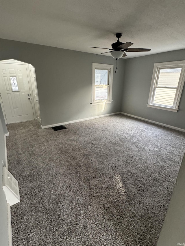 carpeted spare room featuring ceiling fan, a healthy amount of sunlight, and a textured ceiling