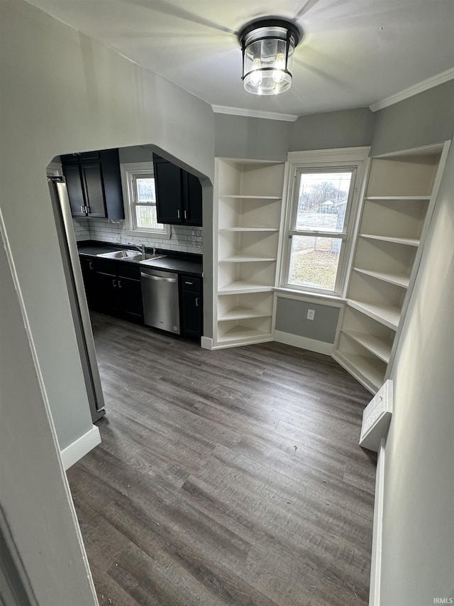 kitchen featuring sink, backsplash, ornamental molding, stainless steel appliances, and dark wood-type flooring