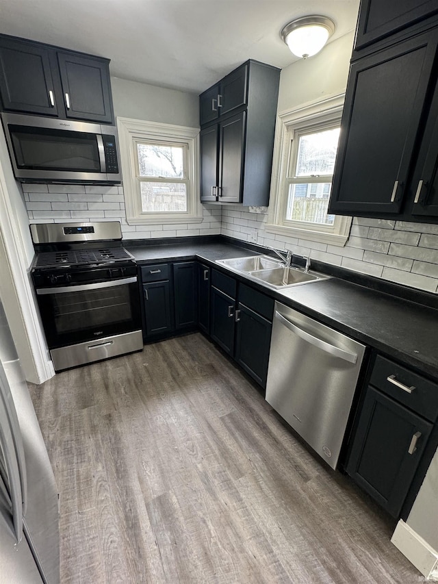 kitchen featuring stainless steel appliances, wood-type flooring, sink, and decorative backsplash