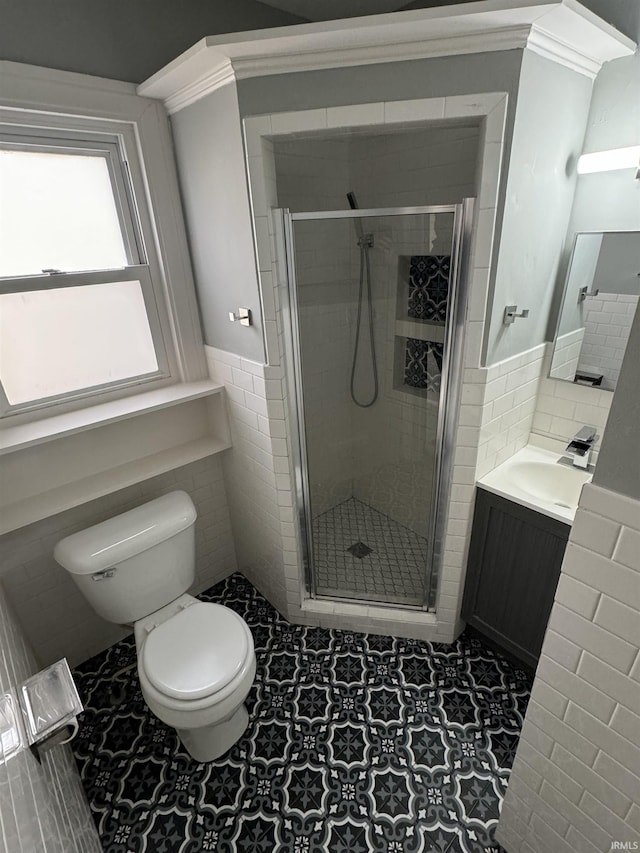 bathroom featuring vanity, toilet, tile walls, and a shower with shower door