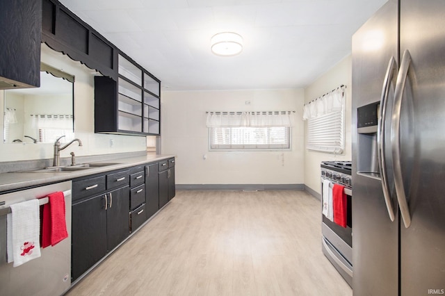 kitchen with appliances with stainless steel finishes, sink, and light hardwood / wood-style floors