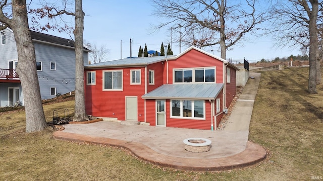 back of property with a patio, a yard, and a fire pit