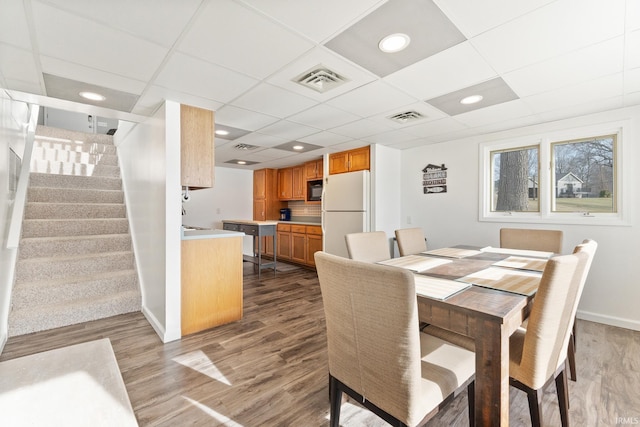 dining area with a drop ceiling and wood-type flooring