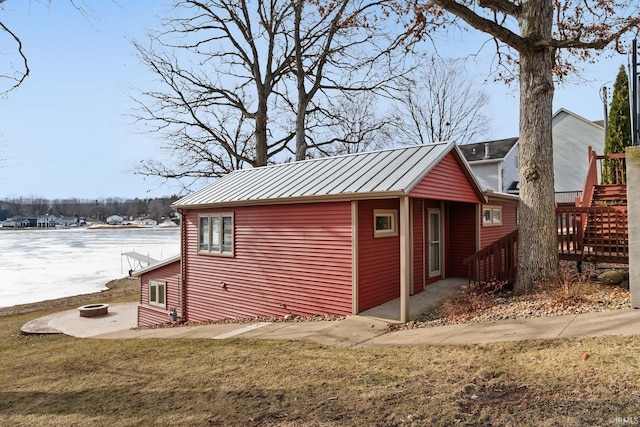 view of home's exterior featuring a fire pit, a lawn, and a water view