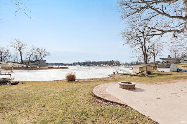 view of yard featuring a water view, an outdoor fire pit, and a storage unit