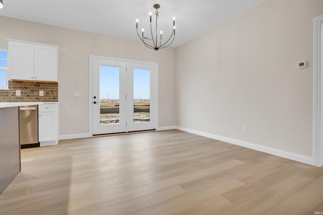 unfurnished dining area featuring a notable chandelier and light wood-type flooring