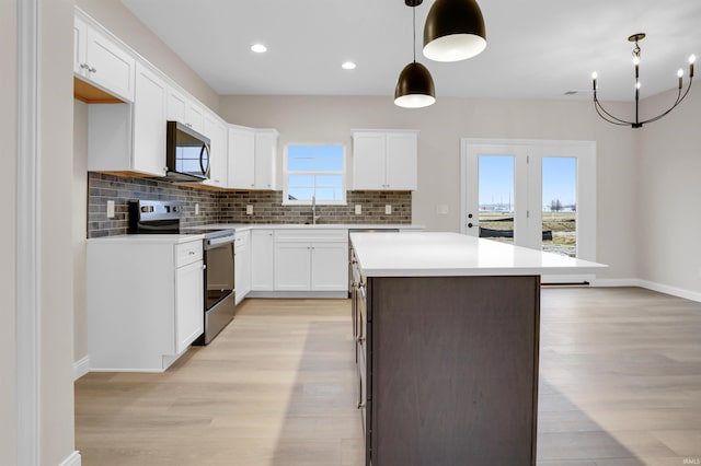 kitchen featuring a kitchen island, appliances with stainless steel finishes, white cabinetry, decorative backsplash, and hanging light fixtures