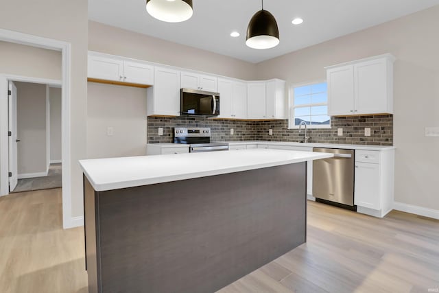 kitchen with white cabinetry, decorative light fixtures, a center island, light hardwood / wood-style flooring, and appliances with stainless steel finishes