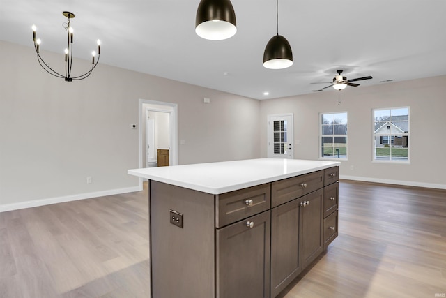 kitchen with ceiling fan, a center island, light hardwood / wood-style floors, and hanging light fixtures