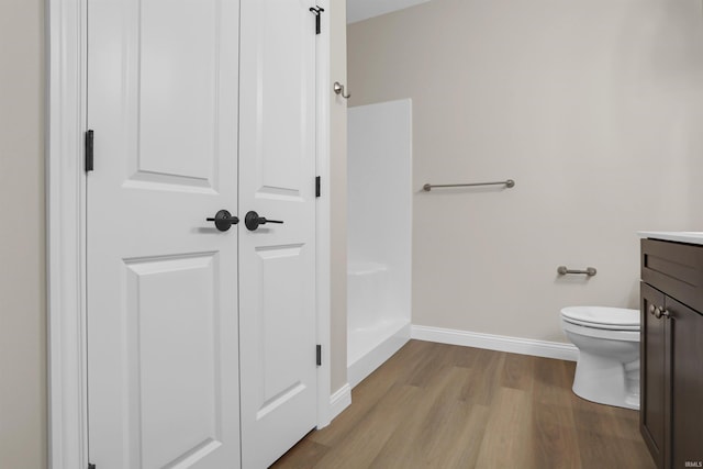 bathroom with hardwood / wood-style flooring, vanity, walk in shower, and toilet