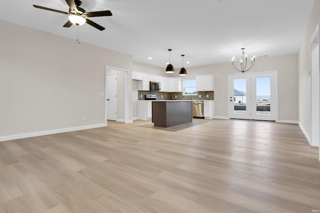 unfurnished living room with sink, ceiling fan with notable chandelier, and light hardwood / wood-style flooring