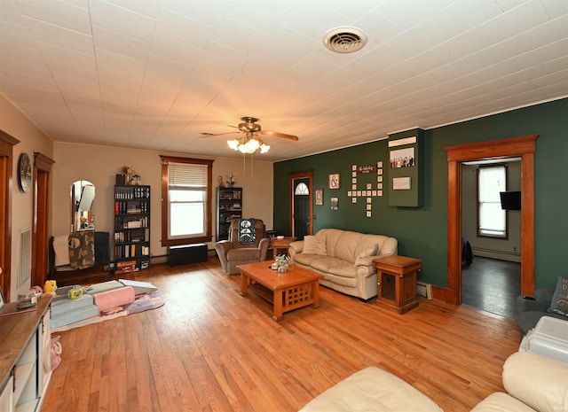 living room with a baseboard heating unit, ceiling fan, and light hardwood / wood-style flooring