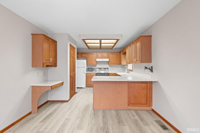 kitchen featuring sink, range, light wood-type flooring, kitchen peninsula, and white fridge