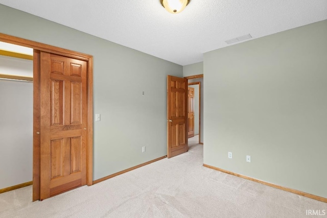 unfurnished bedroom featuring light colored carpet, a closet, and a textured ceiling