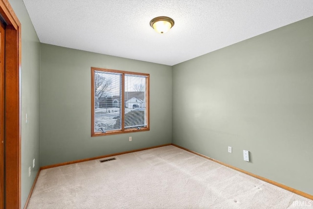 empty room with light carpet and a textured ceiling