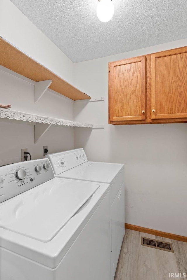 laundry area with separate washer and dryer, light hardwood / wood-style flooring, cabinets, and a textured ceiling