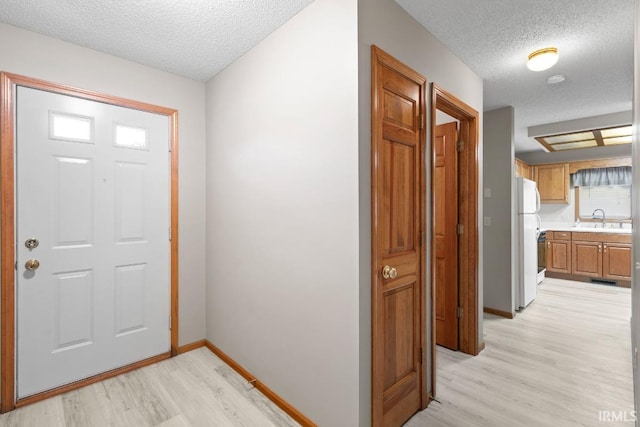 foyer featuring sink, a textured ceiling, and light wood-type flooring