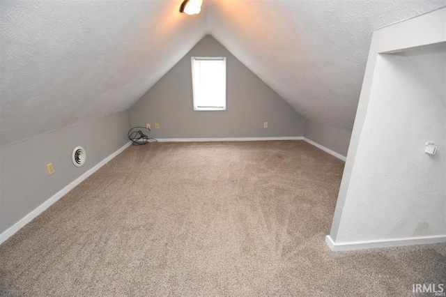 bonus room featuring vaulted ceiling, a textured ceiling, and carpet