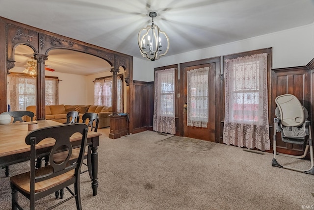 dining space featuring a chandelier, decorative columns, and light carpet