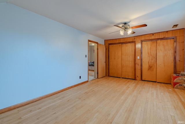 unfurnished bedroom with ceiling fan, two closets, and light hardwood / wood-style floors