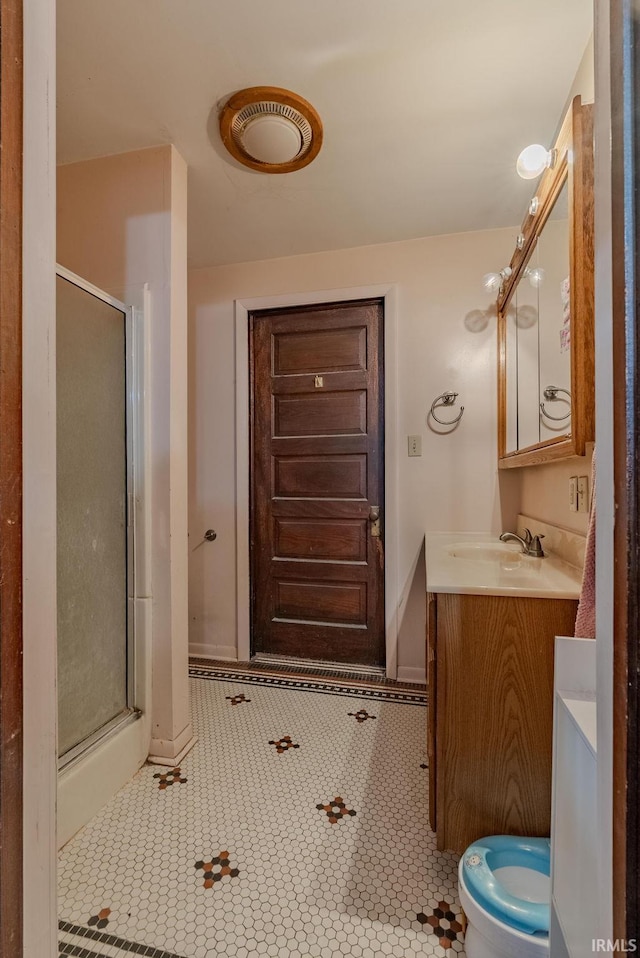 bathroom with tile patterned floors, toilet, a shower with door, and vanity