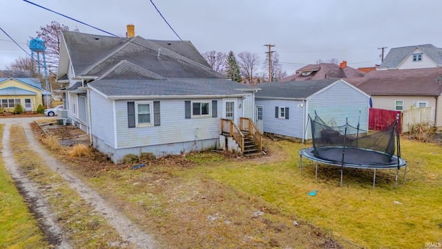 back of house with a trampoline and a lawn