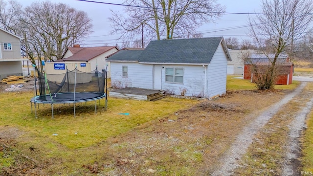 back of house with a trampoline and a lawn