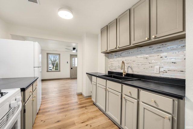 kitchen with sink, decorative backsplash, gray cabinets, and white electric range oven