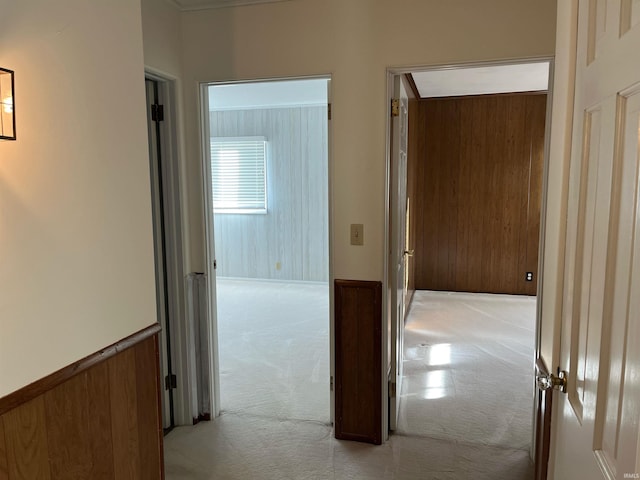 hallway with light carpet and wood walls