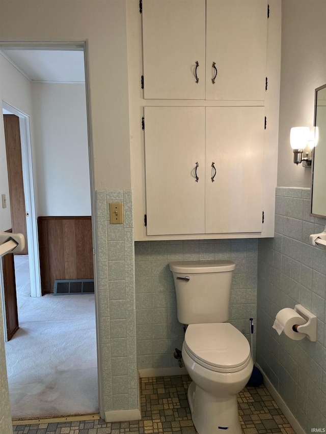 bathroom with toilet and tile walls