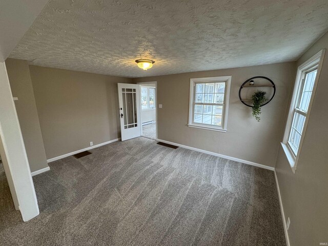 empty room with carpet floors, a textured ceiling, and baseboard heating