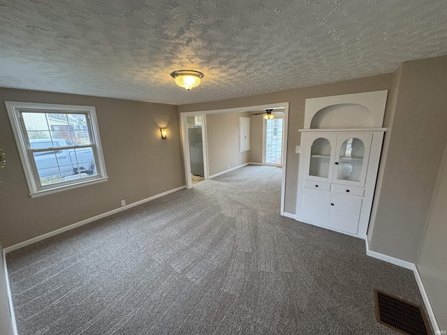 carpeted spare room featuring ceiling fan and a textured ceiling