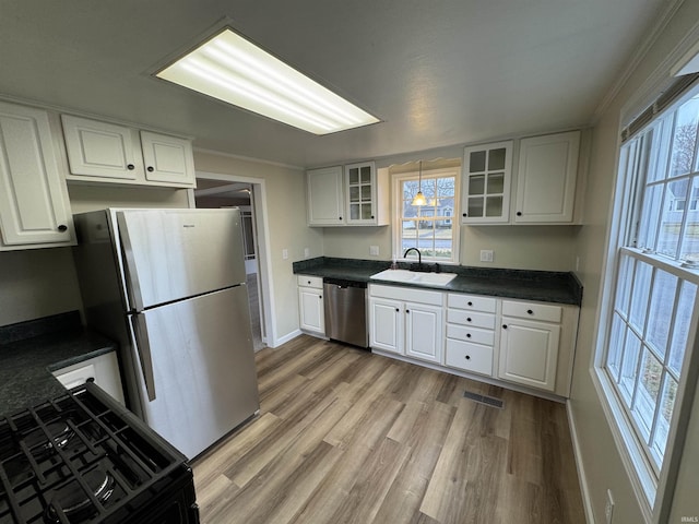 kitchen with pendant lighting, sink, stainless steel appliances, light hardwood / wood-style floors, and white cabinets