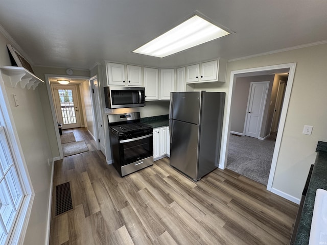 kitchen with white cabinetry, crown molding, light wood-type flooring, and appliances with stainless steel finishes