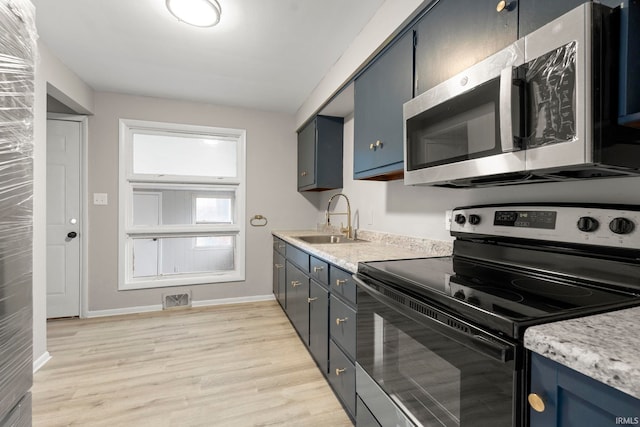 kitchen with stainless steel appliances, sink, blue cabinets, and light hardwood / wood-style flooring