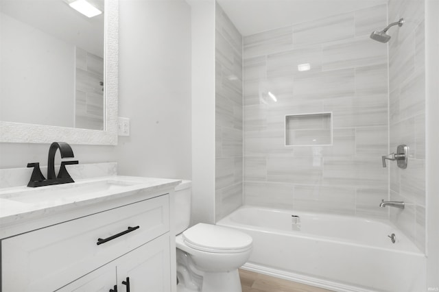 full bathroom with vanity, tiled shower / bath combo, toilet, and hardwood / wood-style flooring