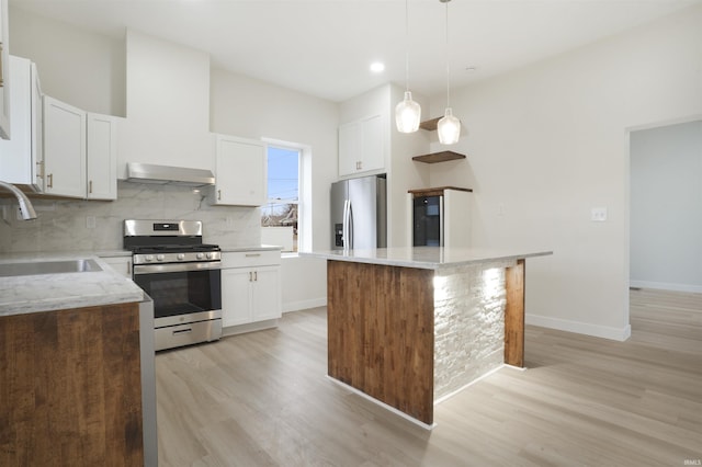 kitchen with pendant lighting, sink, appliances with stainless steel finishes, white cabinetry, and a center island