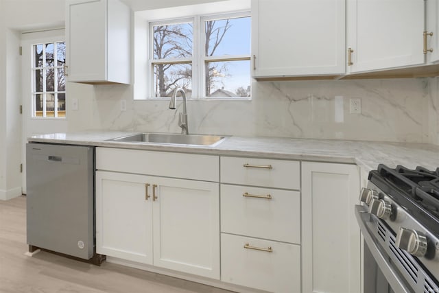 kitchen with light stone counters, appliances with stainless steel finishes, sink, and white cabinets