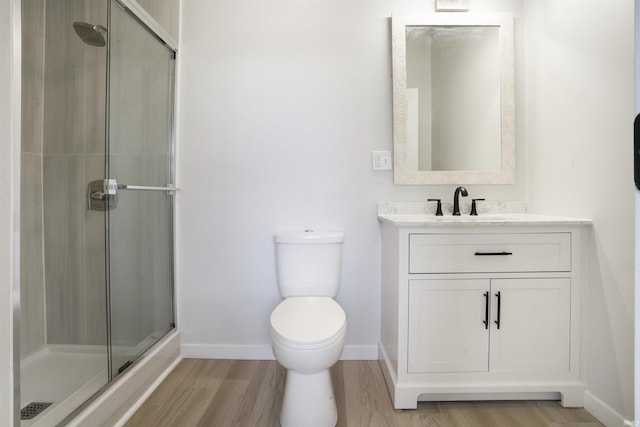 bathroom with vanity, hardwood / wood-style flooring, a shower with shower door, and toilet