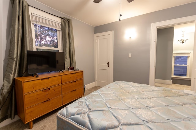 carpeted bedroom with ceiling fan with notable chandelier