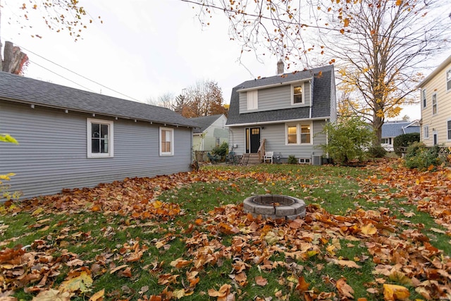 rear view of property featuring a yard and an outdoor fire pit