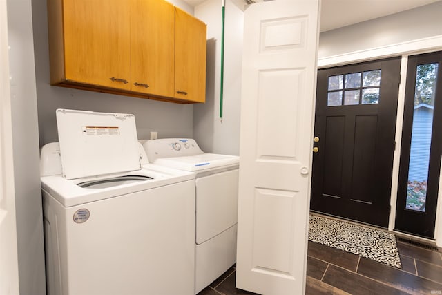 clothes washing area featuring independent washer and dryer and cabinets