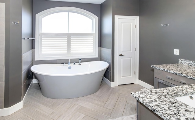 bathroom featuring vanity, tile walls, parquet floors, and a tub to relax in