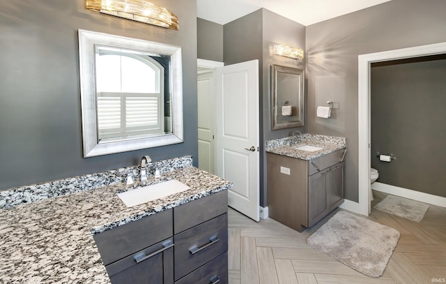 bathroom with parquet flooring, vanity, and toilet