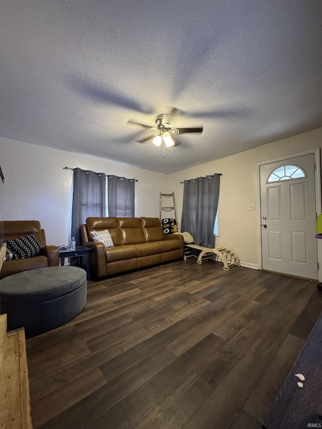 living room featuring dark wood-type flooring, ceiling fan, and a textured ceiling